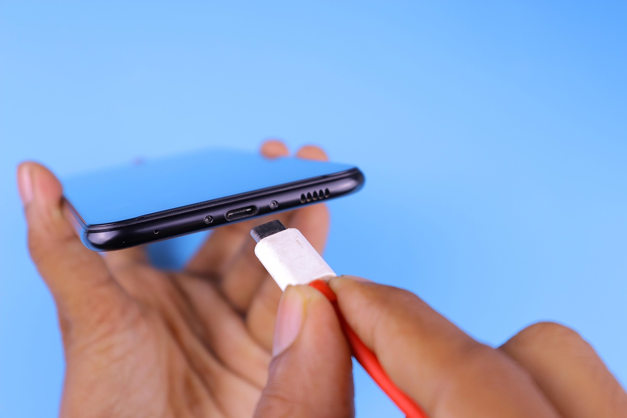 Caricabatterie difettoso che può danneggiare un telefono, con avviso di sicurezza sullo sfondo.