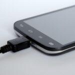 Caricabatterie per telefono collegato a una presa elettrica di notte con bolletta in evidenza.